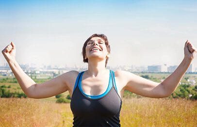 A woman with her arms outstretched in the middle of a field.