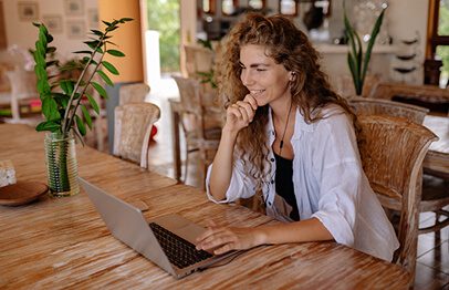 A woman sitting at a table with her laptop.