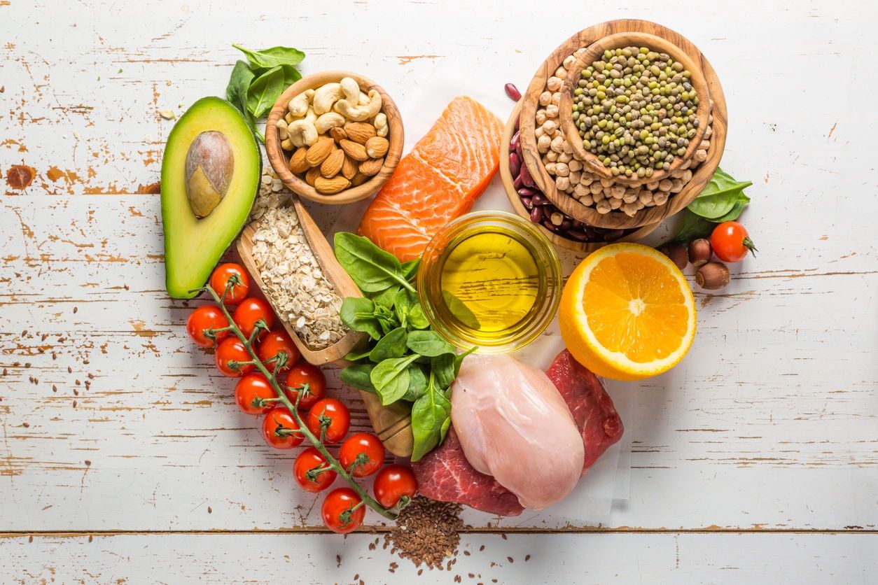 A heart shaped plate of food including meat, vegetables and nuts.